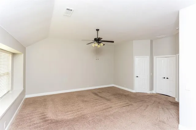 a view of a room with a ceiling fan and window