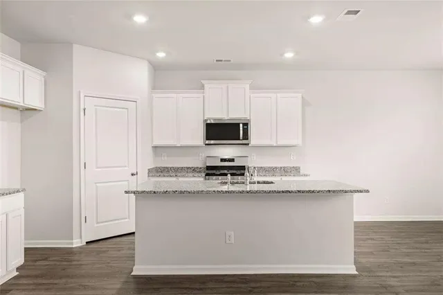 a kitchen with stainless steel appliances granite countertop a stove a sink and a microwave