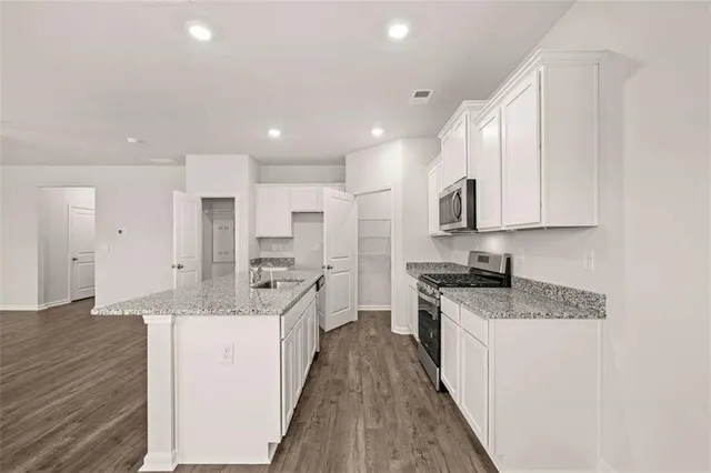 a large kitchen with stainless steel appliances lots of counter space and wooden floor