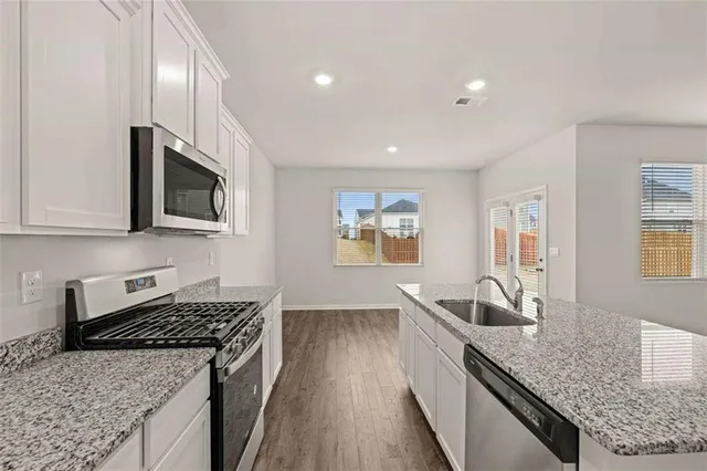 a kitchen with stainless steel appliances granite countertop a sink stove and microwave