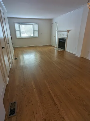 an empty room with wooden floor fireplace and windows