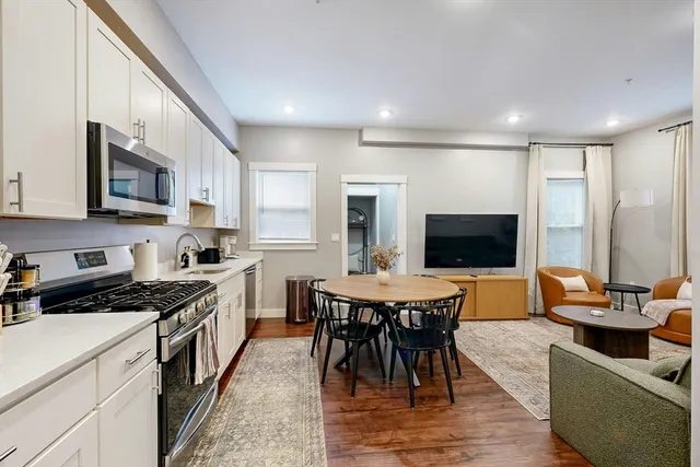 a kitchen with stainless steel appliances granite countertop a stove a sink a microwave a dining table and chairs