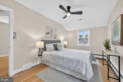 a bedroom with a bed a dresser and wooden floor