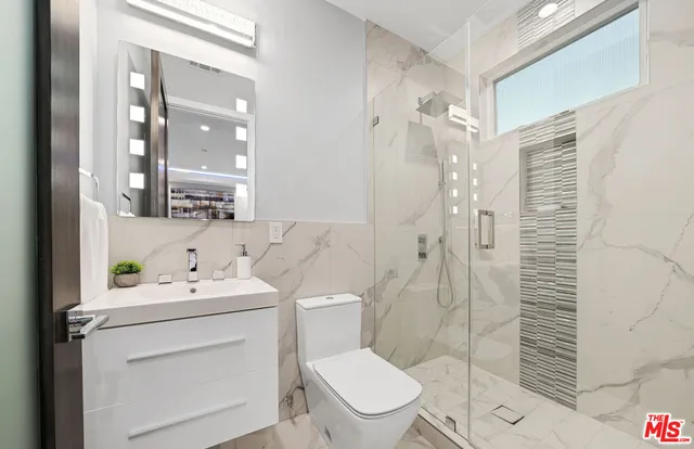 a bathroom with a toilet sink vanity and shower
