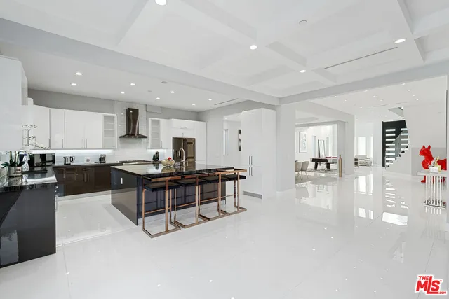 a large white kitchen with stainless steel appliances granite countertop a stove and a sink