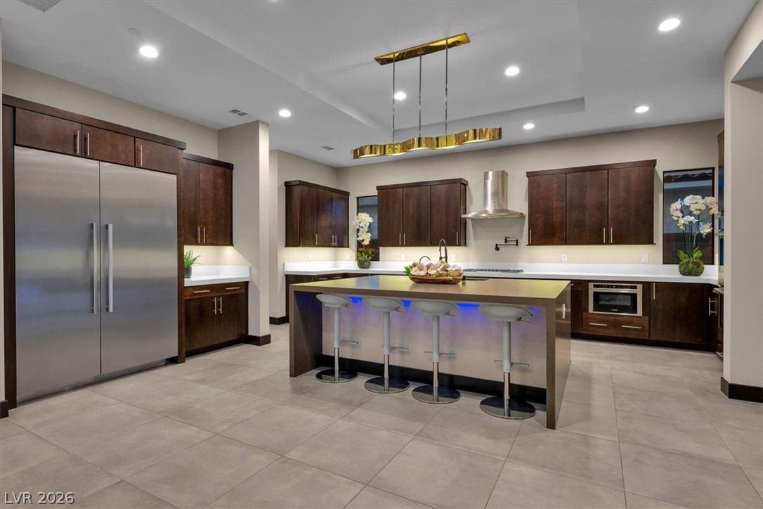 53 Garibaldi Way Henderson, NV 89011 - Photo 17 of 80 Kitchen featuring dark brown cabinetry, stainless steel built in fridge, a breakfast bar, decorative light fixtures, and recessed lighting