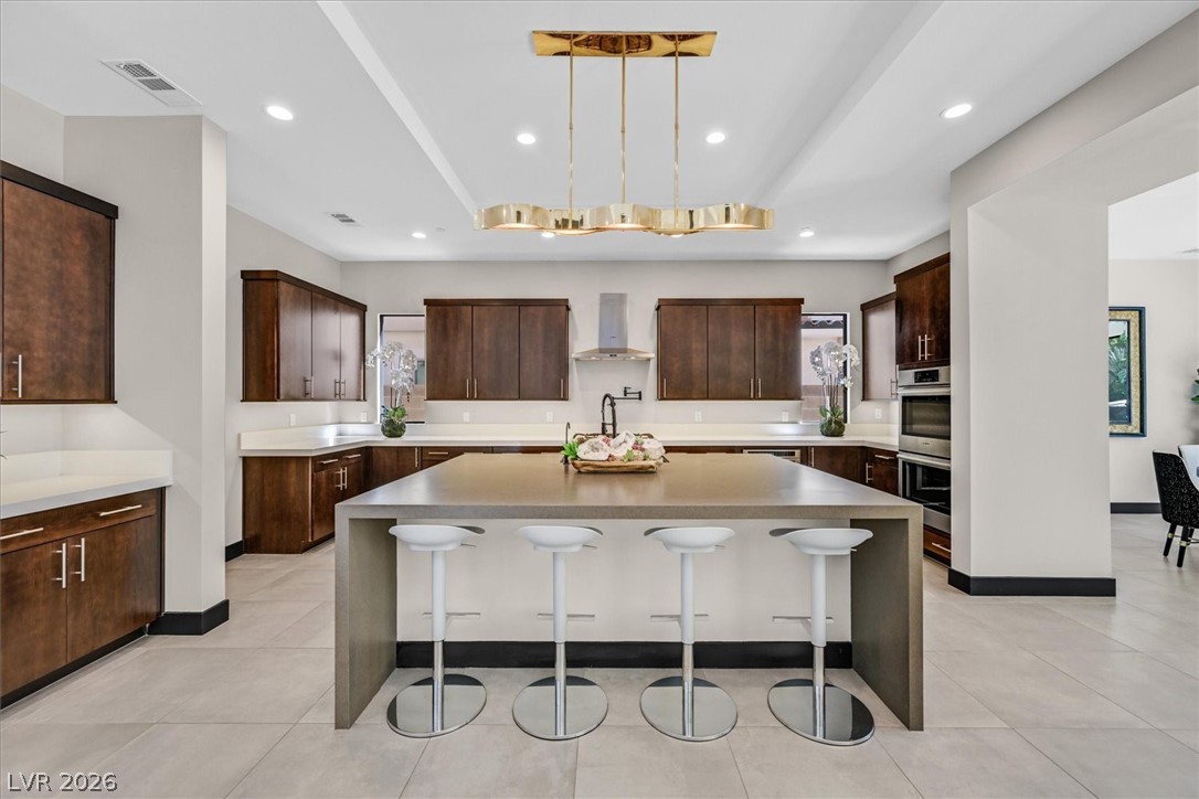 53 Garibaldi Way Henderson, NV 89011 - Photo 20 of 80 Kitchen with a center island, light stone countertops, dark brown cabinetry, a kitchen breakfast bar, and recessed lighting