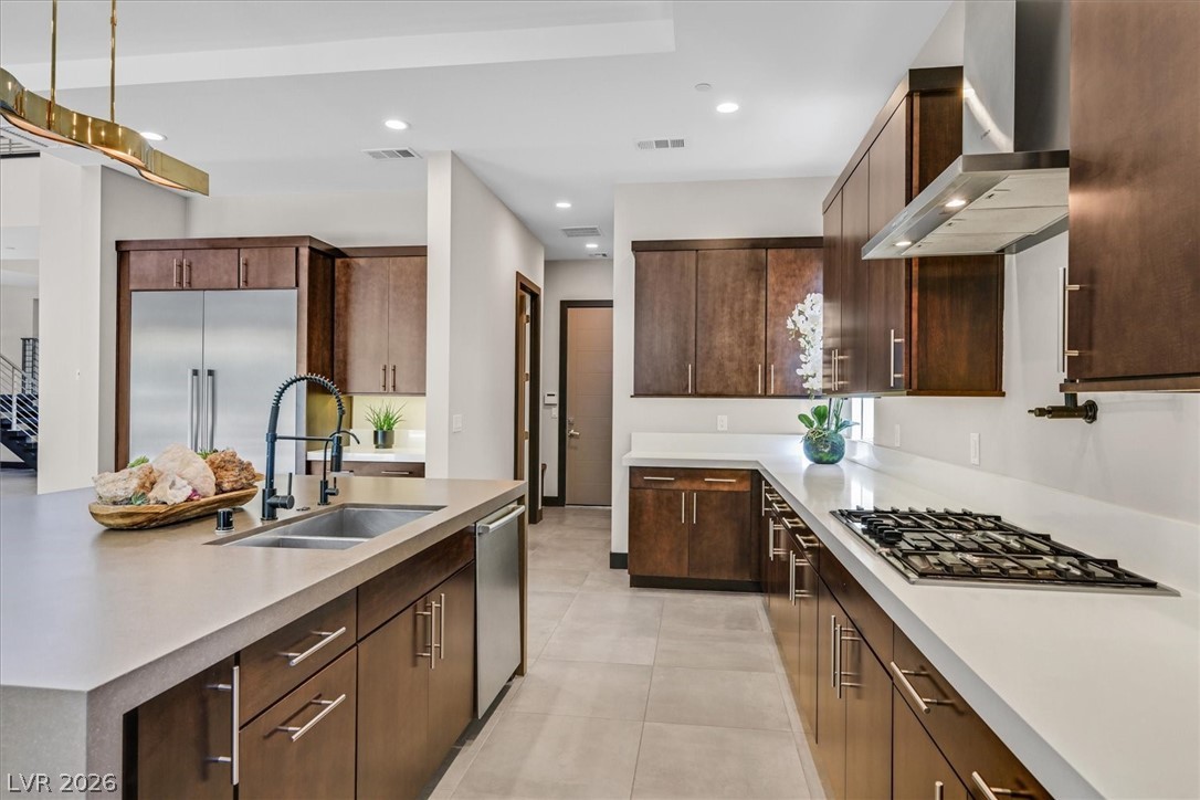 53 Garibaldi Way Henderson, NV 89011 - Photo 22 of 80 Kitchen featuring a center island with sink, wall chimney exhaust hood, appliances with stainless steel finishes, hanging light fixtures, and recessed lighting