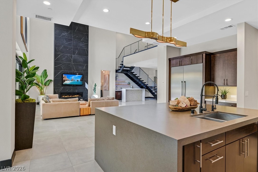 53 Garibaldi Way Henderson, NV 89011 - Photo 80 of 80 Kitchen with a premium fireplace, a kitchen island with sink, recessed lighting, open floor plan, and dark brown cabinets