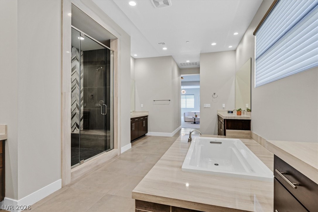53 Garibaldi Way Henderson, NV 89011 - Photo 37 of 80 Full bath with two vanities, a stall shower, recessed lighting, a freestanding bath, and light tile patterned floors