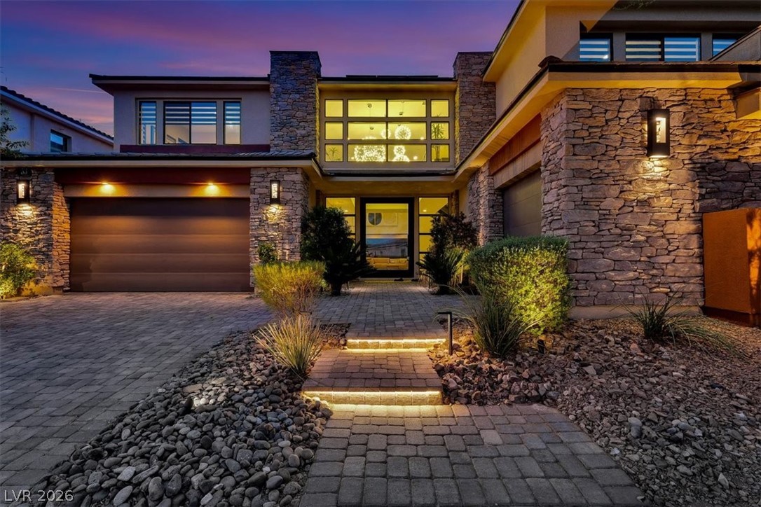 53 Garibaldi Way Henderson, NV 89011 - Photo 5 of 80 View of exterior entry featuring stone siding, stucco siding, and decorative driveway