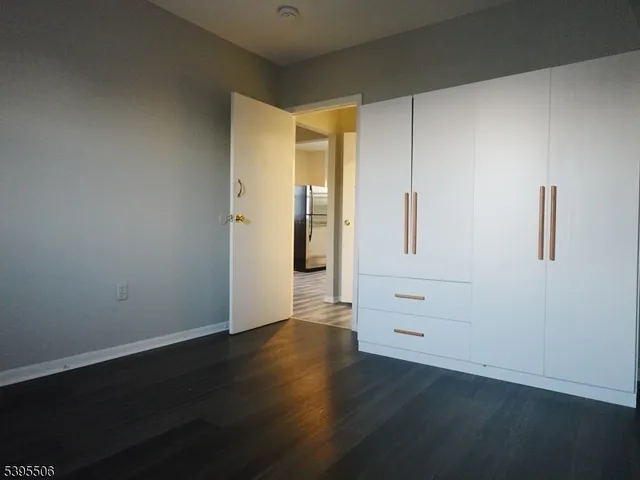 a view of an empty room with wooden floor and closet