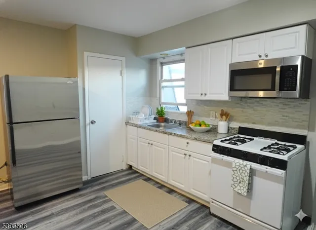 a kitchen with granite countertop stainless steel appliances a sink stove top oven and refrigerator