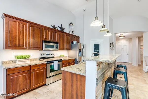 a kitchen with stainless steel appliances granite countertop a stove top oven a sink dishwasher and a refrigerator with wooden cabinets