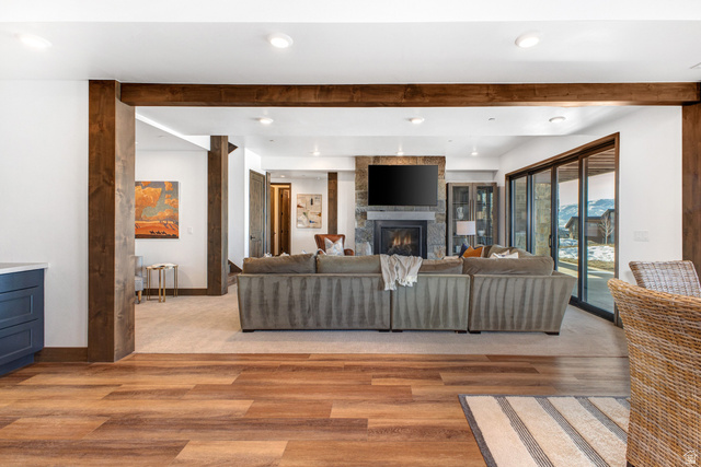 1282 Chimney Rock Road, Unit 344 Heber City, UT 84032 - Photo 33 of 55 Open-concept living area featuring exposed wood beams, a stone-clad fireplace, and expansive sliding glass doors