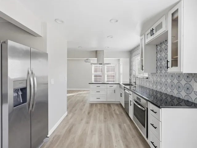a kitchen with granite countertop a sink stove and refrigerator