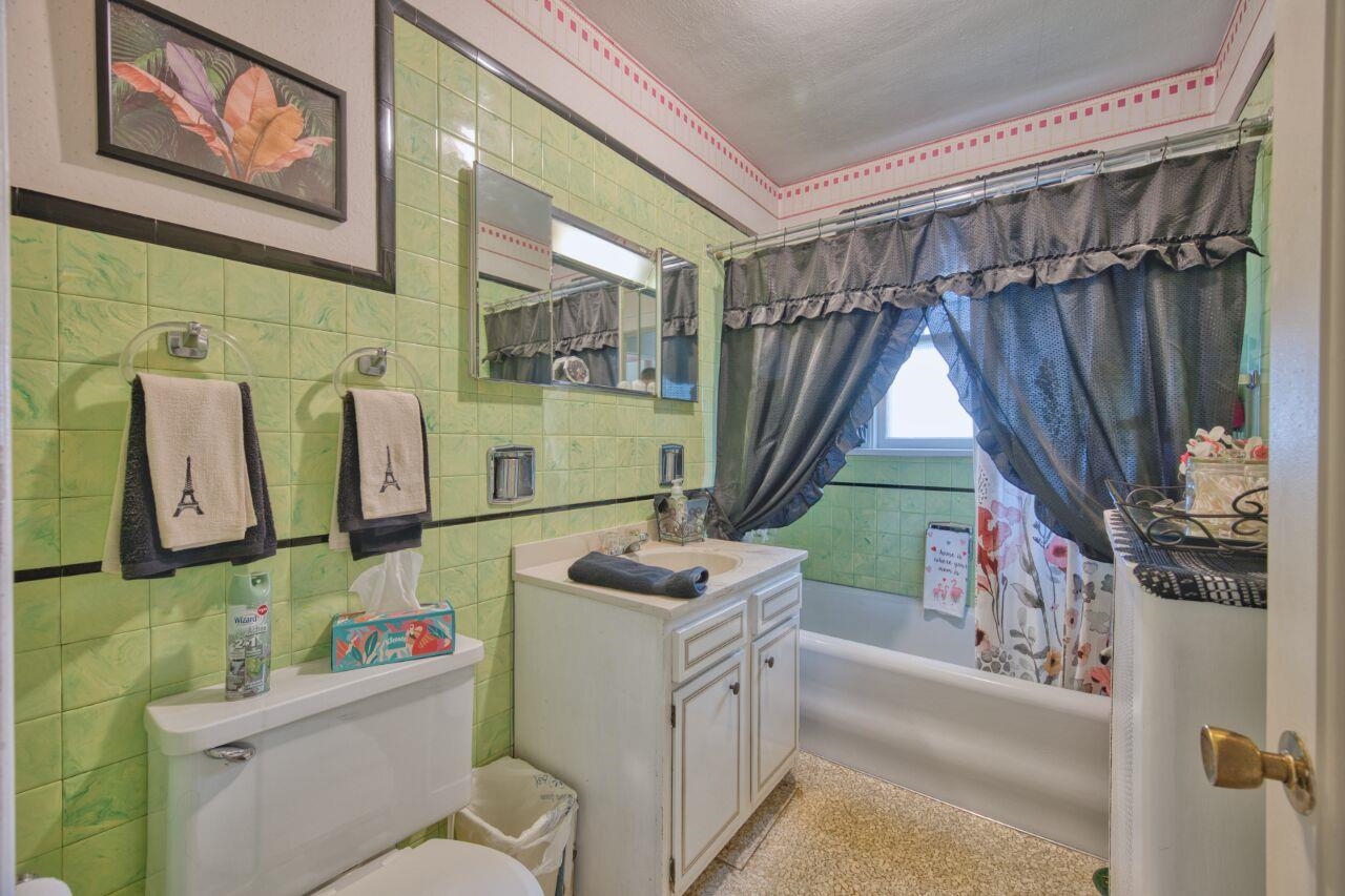 701 Grant Avenue Eveleth, MN 55734 - Photo 28 of 50 Bathroom with vanity, tile walls, shower / bath combo with shower curtain, and backsplash