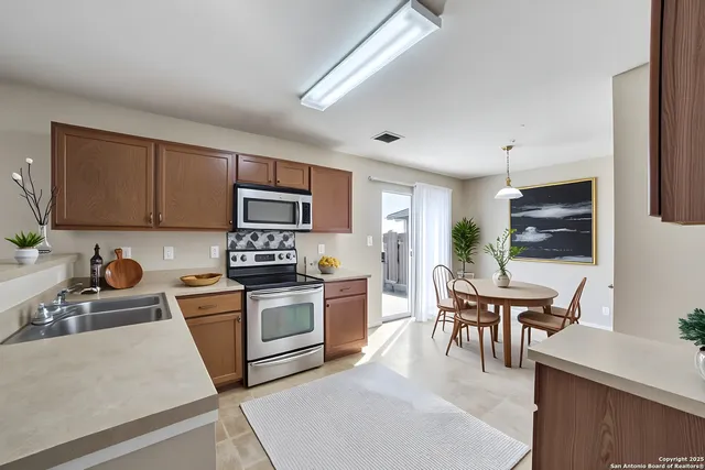 a kitchen with stainless steel appliances granite countertop a stove top oven a sink dishwasher a dining table and chairs with wooden floor