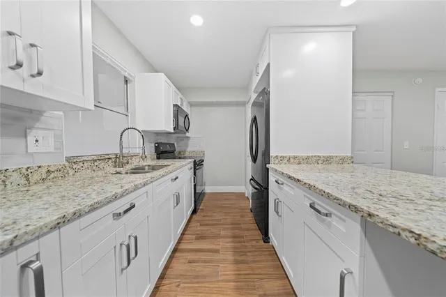 a large kitchen with granite countertop lots of counter top space sink and stainless steel appliances