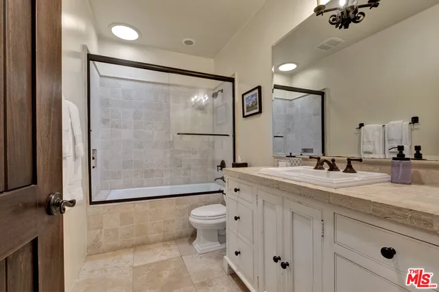a bathroom with a double vanity sink toilet mirror and shower