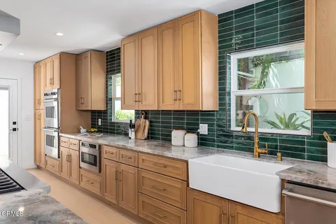 a kitchen with stainless steel appliances granite countertop a sink a stove and a wooden cabinets