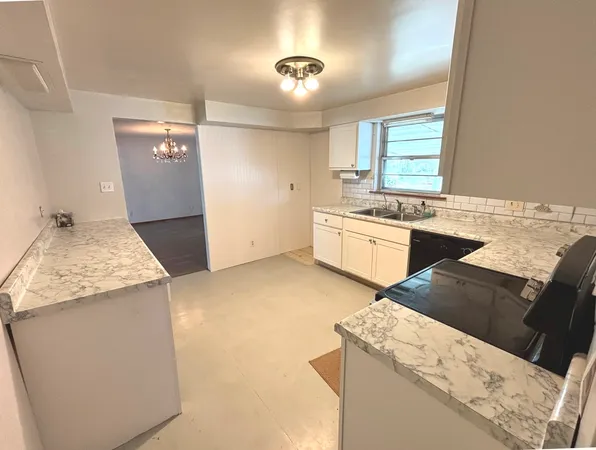 a kitchen with granite countertop a sink stove and refrigerator