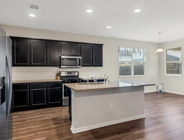 a kitchen with stainless steel appliances granite countertop a stove a sink and a microwave