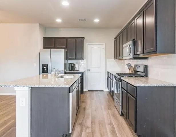 a kitchen with stainless steel appliances granite countertop a refrigerator a stove a sink and a microwave