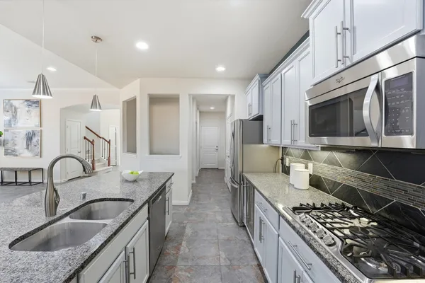 a kitchen with a stove a sink a refrigerator and chairs