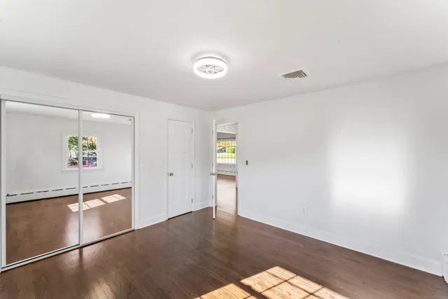 an empty room with wooden floor and window