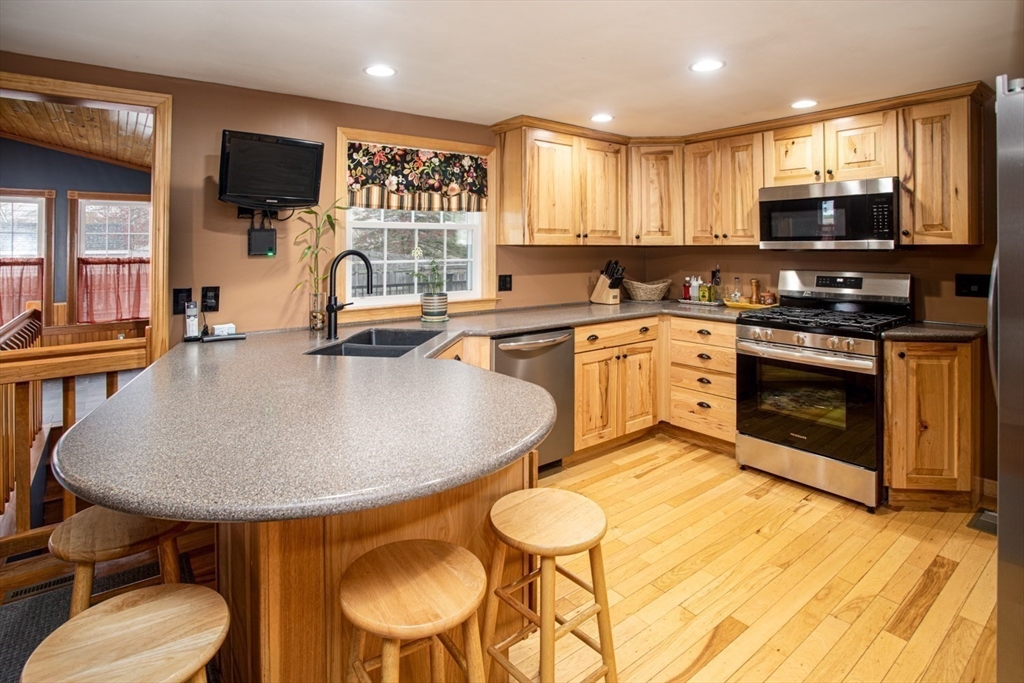204 Riley Avenue Somerset, MA 02726 - Photo 9 of 31 a kitchen with stainless steel appliances granite countertop a sink a stove a microwave a center island and chairs