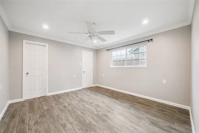an empty room with wooden floor ceiling fan and windows