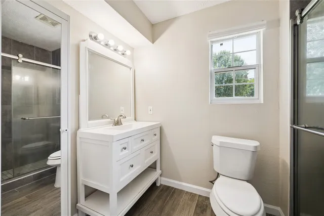 a bathroom with a toilet a sink and glass door