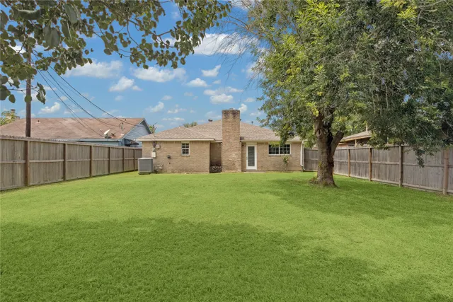 a view of a white house in front of a big yard with large trees