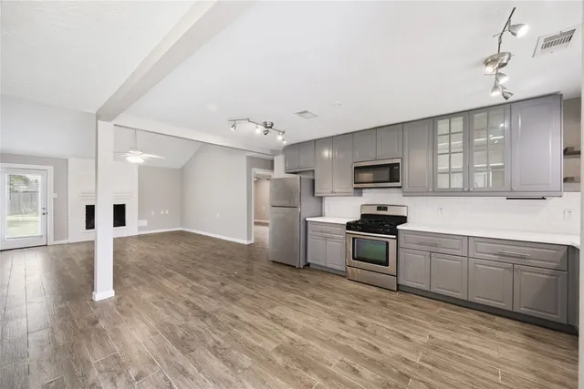 a large kitchen with cabinets wooden floor and stainless steel appliances