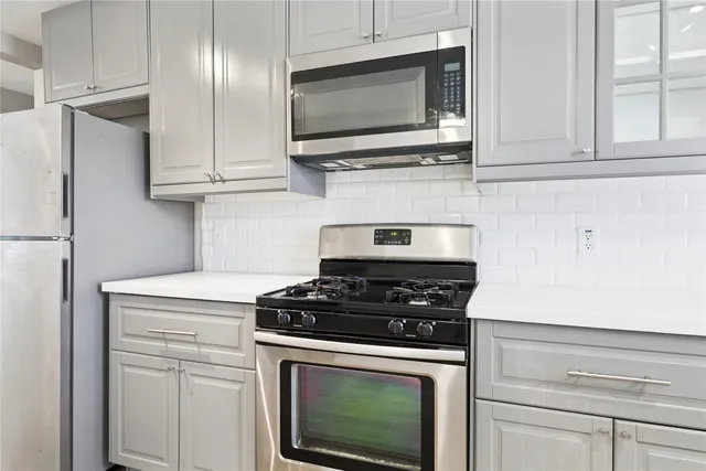 a kitchen with stainless steel appliances granite countertop white cabinets and a stove top oven
