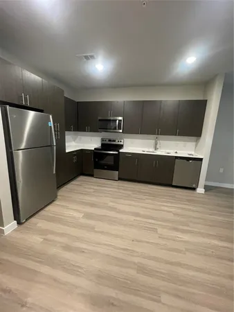 a view of kitchen with stainless steel appliances wooden floor and chandelier
