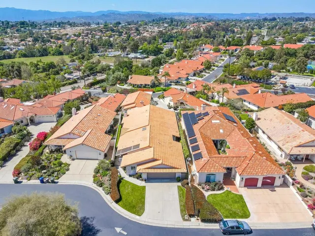 an aerial view of residential houses with outdoor space and parking