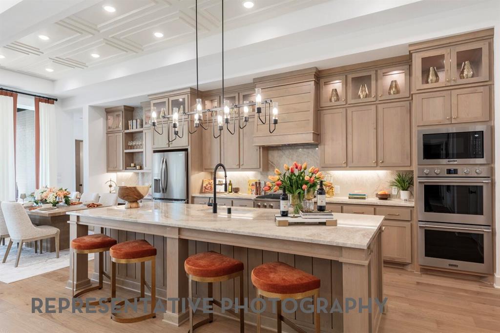 3808 Meander Way Prosper, TX 75078 - Photo 2 of 40 a kitchen with stainless steel appliances kitchen island granite countertop a table chairs in it and wooden floors