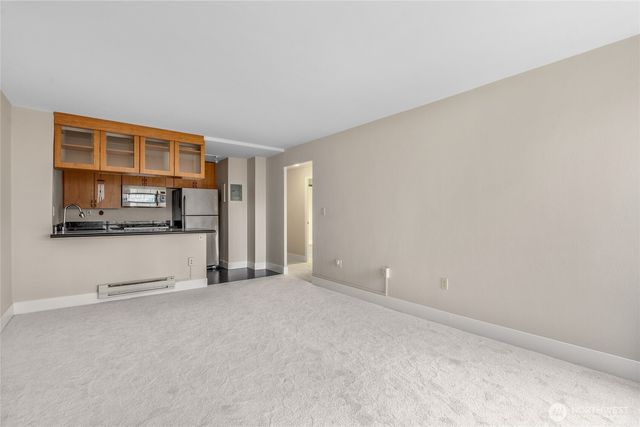 a view of an empty room with kitchen cabinet and window