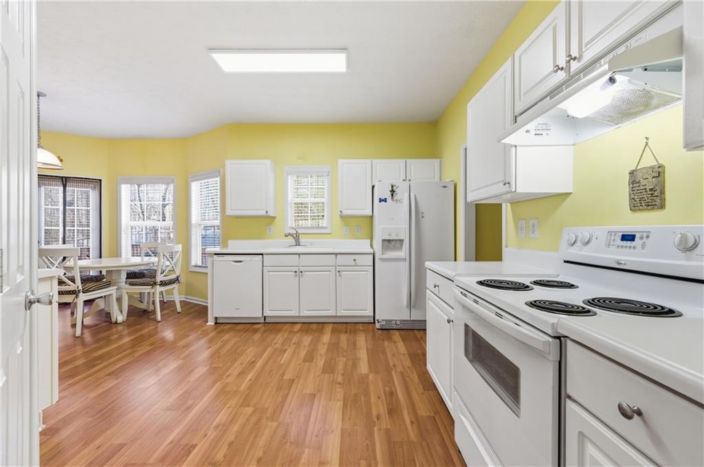 5980 Giles Road Lithonia, GA 30058 - Photo 12 of 38 a kitchen with stainless steel appliances a stove a sink and white cabinets with wooden floor