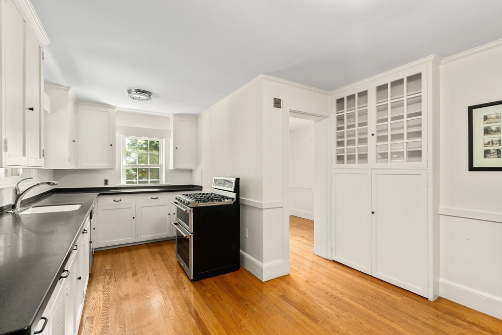 2 Kenilworth Road Wellesley, MA 02482 - Photo 19 of 41 a kitchen with granite countertop a stove a sink and white cabinets with wooden floor