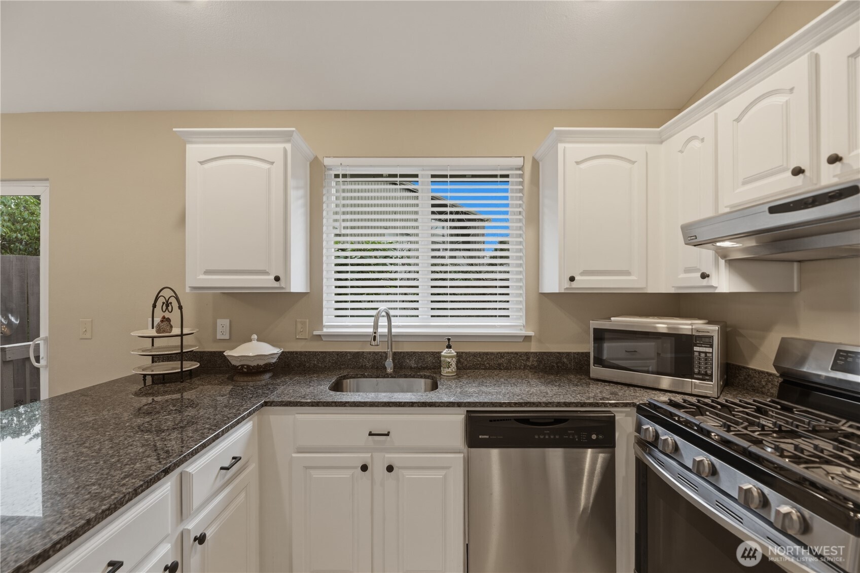 2415 Southeast 8th Place Renton, WA 98057 - Photo 10 of 39 a kitchen with granite countertop a sink a stove and cabinets