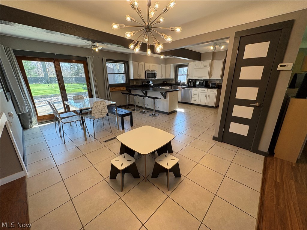 17583 Shurmer Road Strongsville, OH 44136 - Photo 18 of 50 Spacious open-concept living area featuring light-toned square tile flooring, a modern sputnik chandelier, and exposed ceiling beams