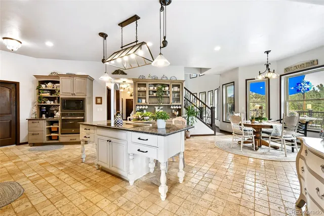 a living room with stainless steel appliances kitchen island granite countertop a stove a sink a dining table and chairs with wooden floor