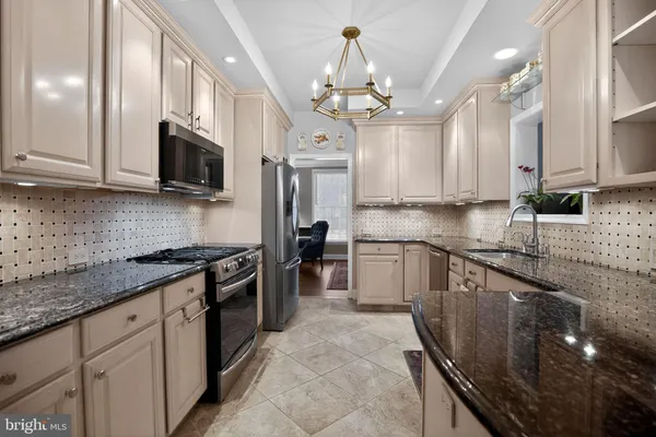 a kitchen with stainless steel appliances granite countertop a sink a stove top oven a counter space and cabinets