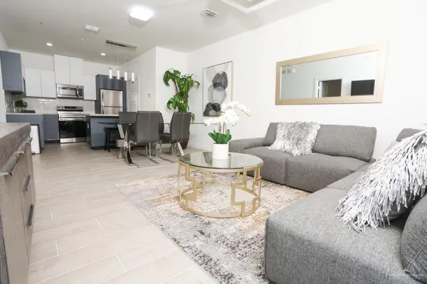 a living room with furniture a kitchen view and a dining table