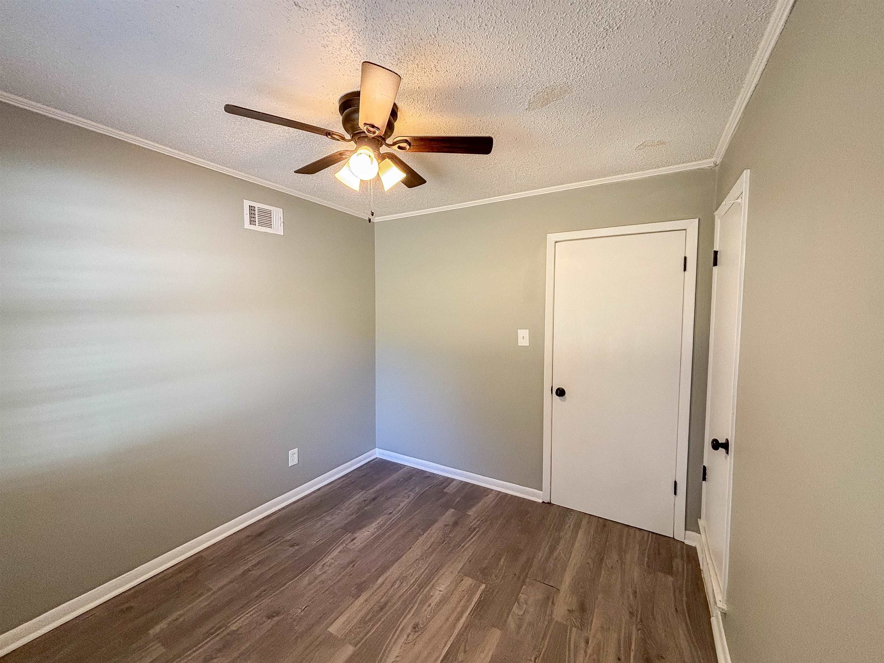 3057 Keats Road Bartlett, TN 38134 - Photo 15 of 23 Empty room featuring a textured ceiling, dark wood finished floors, crown molding, and a ceiling fan