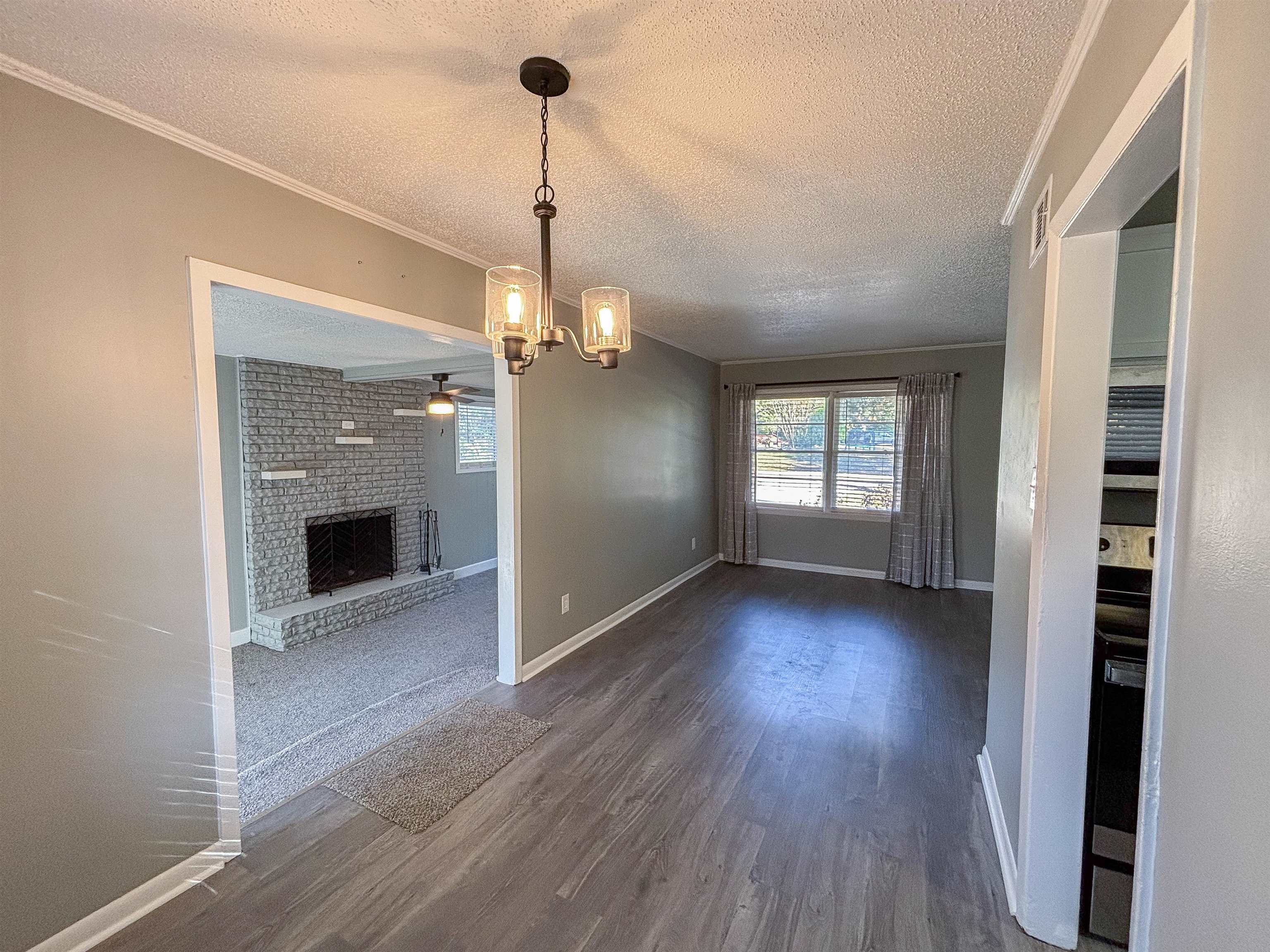 3057 Keats Road Bartlett, TN 38134 - Photo 7 of 23 Unfurnished dining area featuring a textured ceiling, a fireplace, dark wood-style flooring, a ceiling fan, and a chandelier