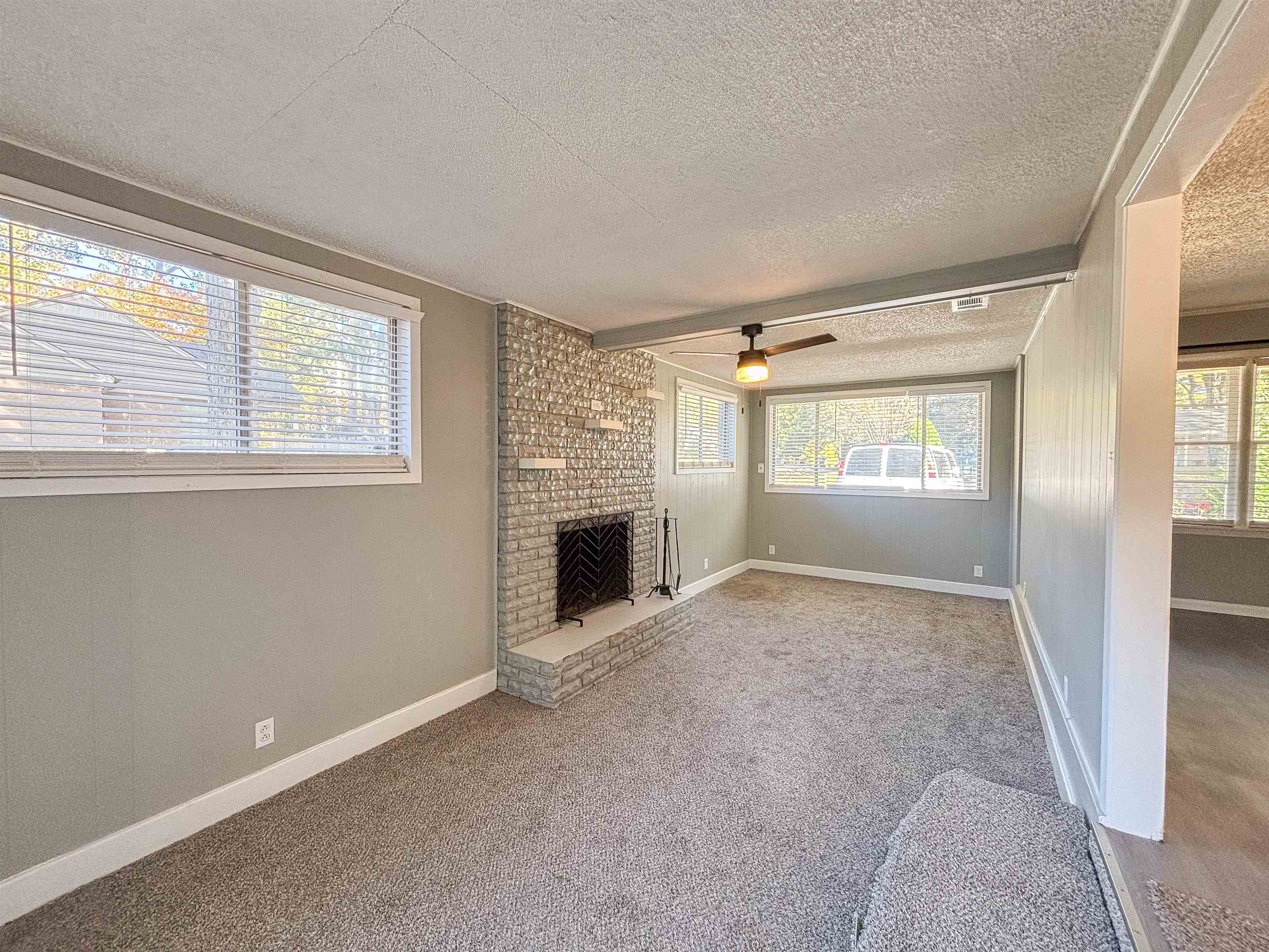3057 Keats Road Bartlett, TN 38134 - Photo 8 of 23 Unfurnished living room with a textured ceiling, carpet floors, a fireplace, a ceiling fan, and beamed ceiling